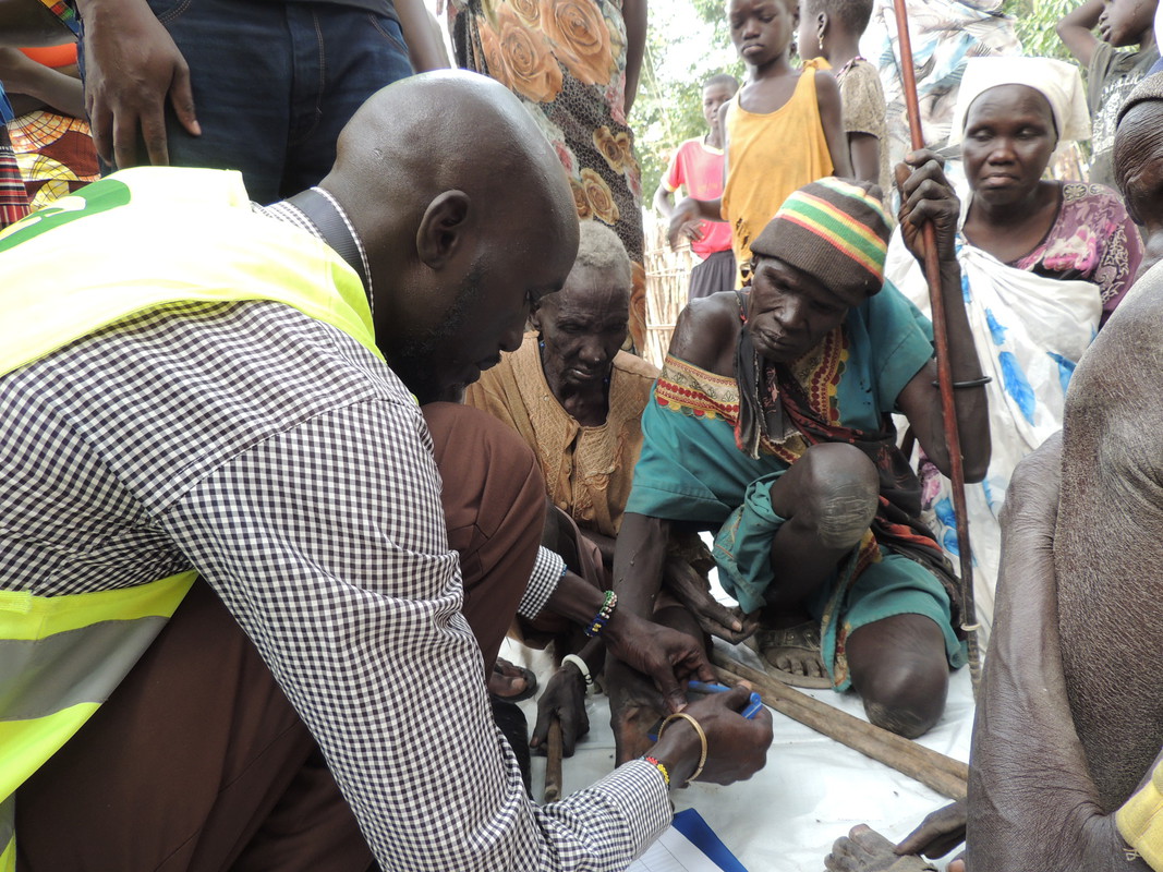 Pedro Marial Rock, miembro del equipo de Oxfam, toma las huellas dactilares a modo de firma de Nyabiey (izquierda) y Nyakonga (derecha) para registrar que recibieron alimentos en la distribución que se llevó a cabo en el 20 de marzo de 2017. Fotografía: L