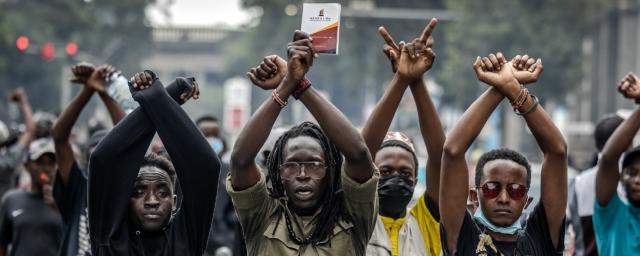 Manifestantes hacen gestos con los brazos delante de agentes de policía de Kenia durante una protesta contra las subidas de impuestos en el centro de Nairobi, mientras en el Parlamento los diputados debaten el Proyecto de Ley de Finanzas de 2024, el 18 de junio de 2024.
