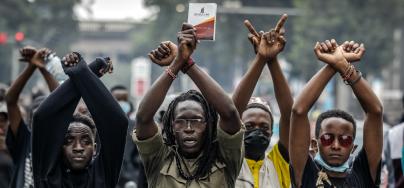 Manifestant·es, poings croisés, devant des agents de police kényans lors d’une manifestation contre la hausse des impôts dans le centre-ville de Nairobi, le 18 juin 2024, alors que les membres du Parlement débattent de la loi de finance 2024.