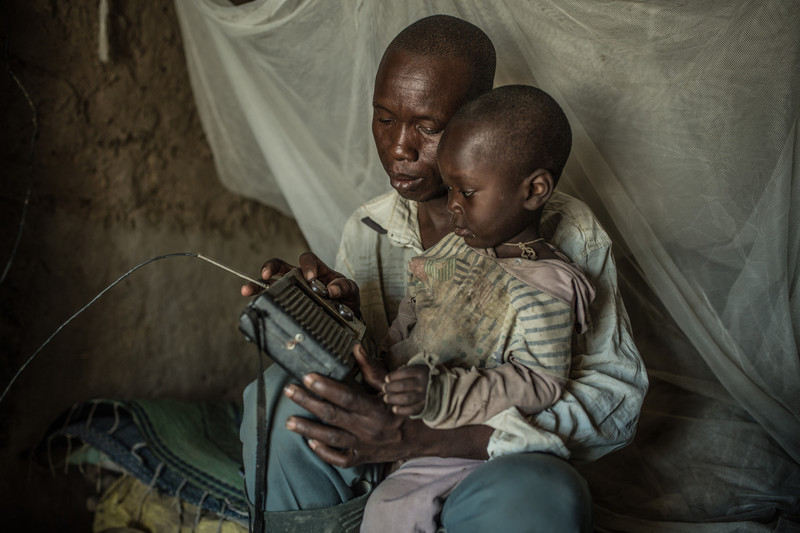 Nabonswendé junto a su hijos escuchando la información meteorológica por la radio
