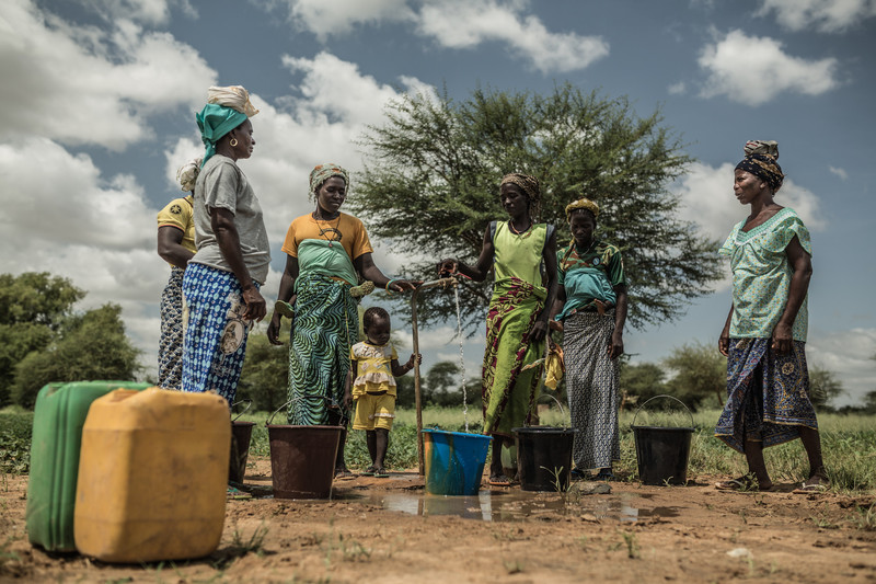 Noaga Ouèda (derecha) junto con otras mujeres de su comunidad recogiendo agua potable de un grifo que se alimenta de la torre de agua que han instalado en su comunidad y que funciona con energía solar. 